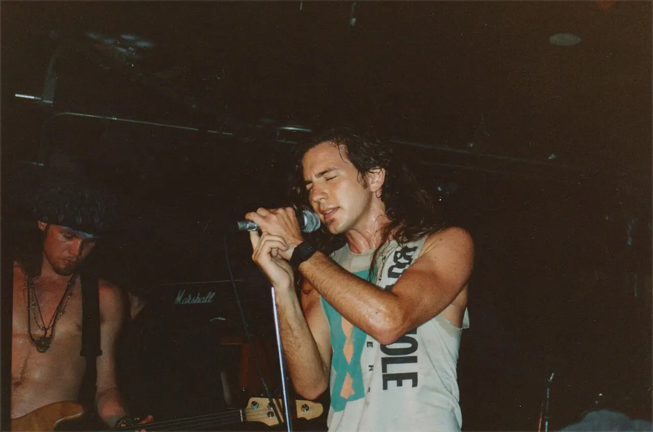Эдди Веддер поёт на концерте Pearl Jam в 1991 году, слева Джефф Амент с бас-гитарой